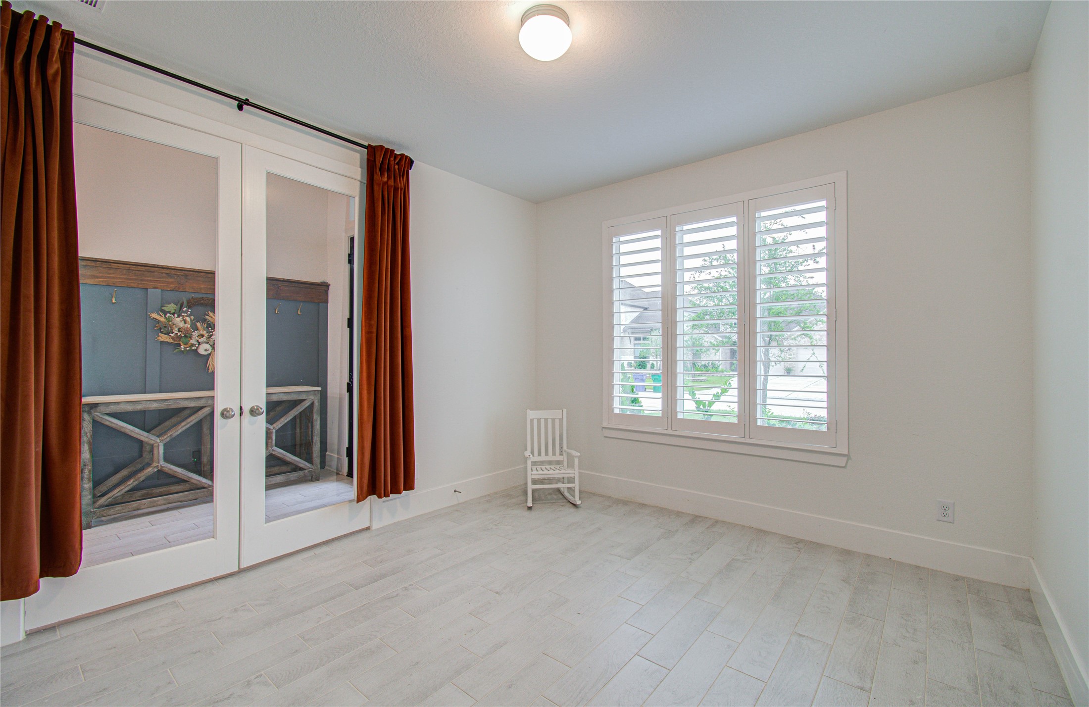 4211 Limestone Terrace Manvel, TX 77578 - Photo 5 of 33 Bright room with light wood flooring, large windows with shutters, and glass doors with red curtains. Cozy and versatile space for an office or small bedroom.
