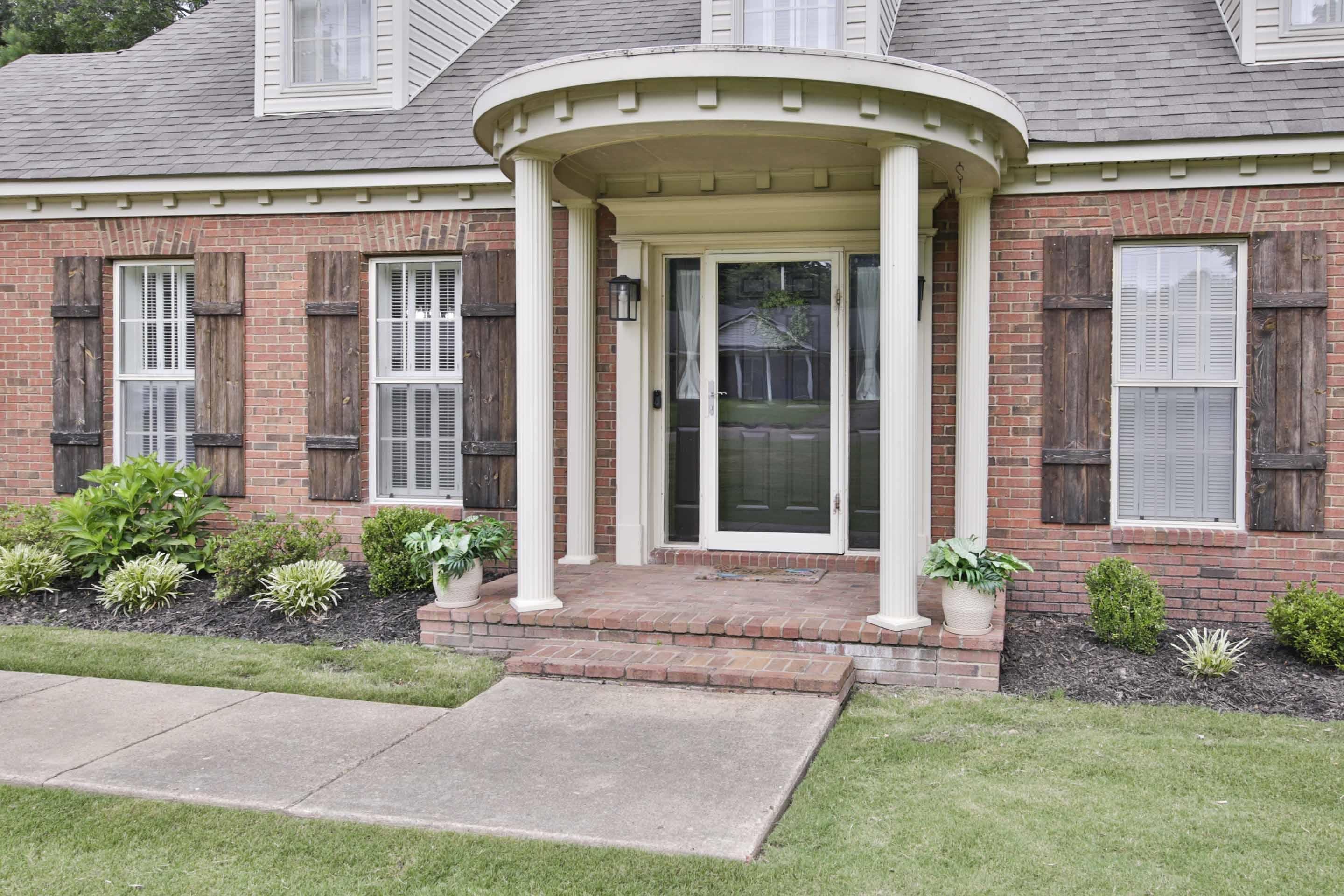 104 Miller Road Covington, TN 38019 - Photo 5 of 25 Brick exterior with a curved portico featuring white columns, a brick entryway, and a dark front door with a storm door