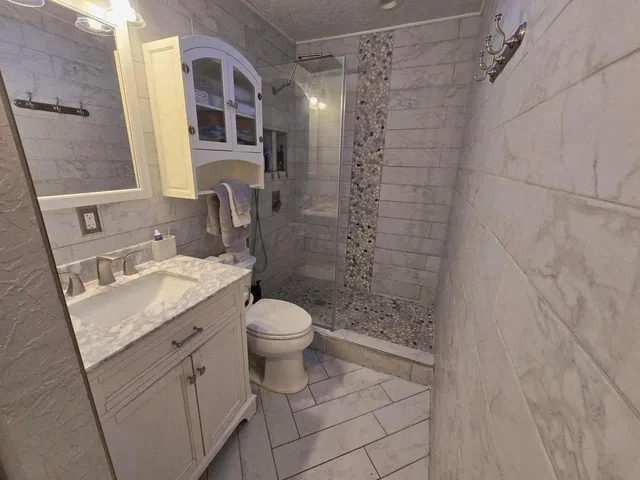 a bathroom with a granite countertop sink toilet and shower