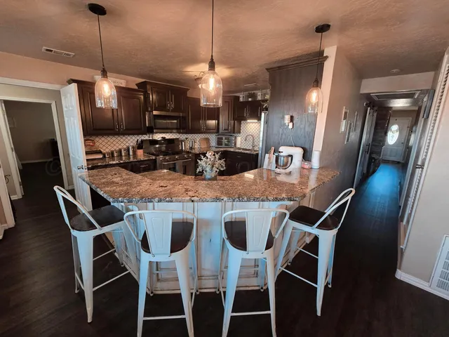 a kitchen with stainless steel appliances granite countertop dining table chairs and wooden floor