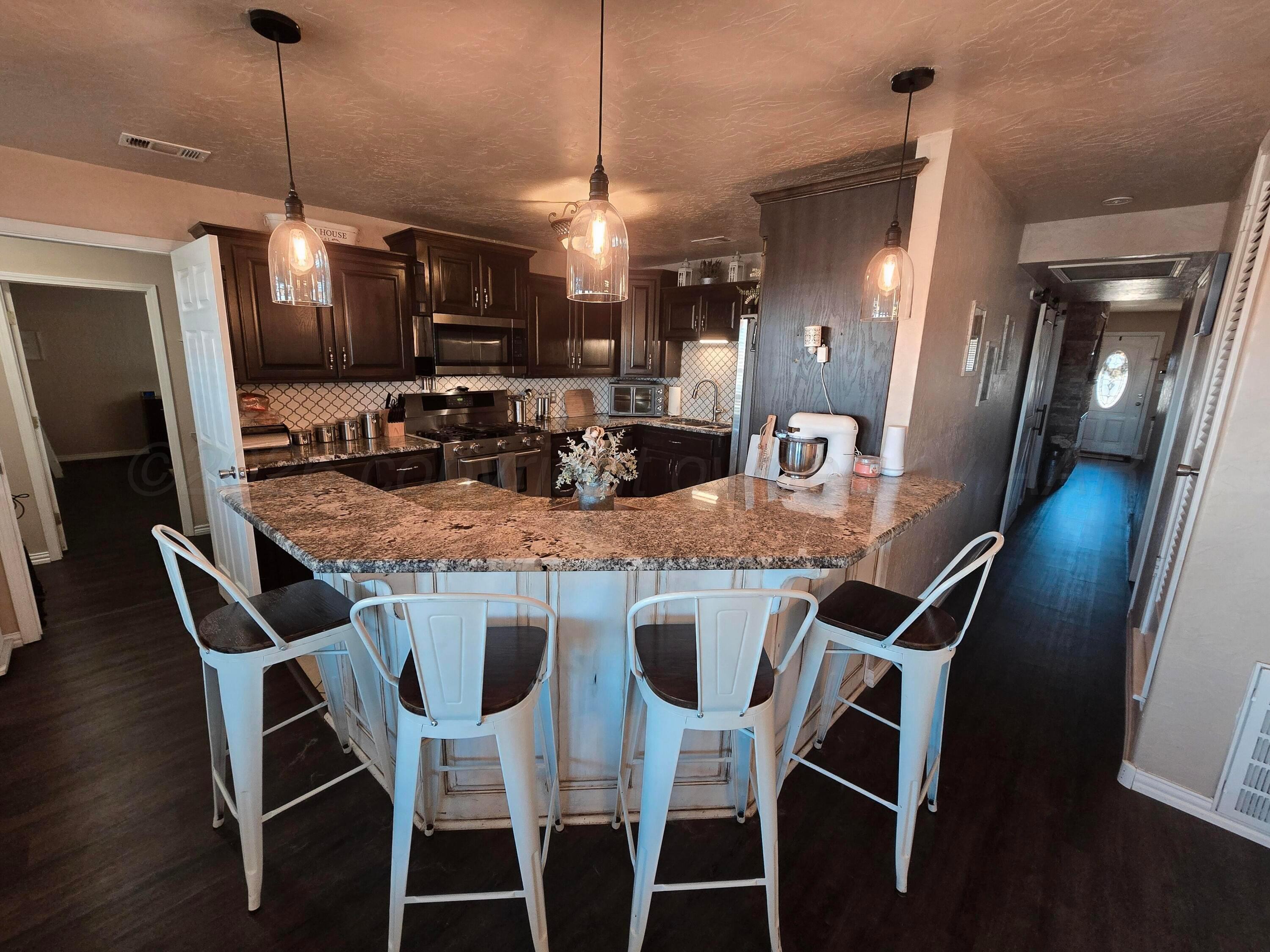 1121 Elmore Street Borger, TX 79007 - Photo 17 of 39 a kitchen with stainless steel appliances granite countertop dining table chairs and wooden floor