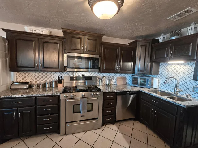 a kitchen with stainless steel appliances granite countertop a sink and stove top oven