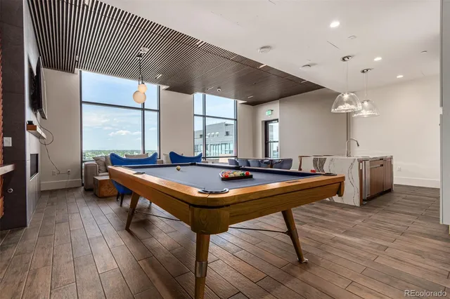 a room with pool table windows and wooden floor