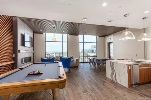 a living room with furniture pool table wooden floor and a large window