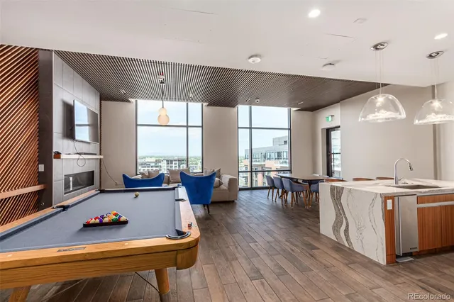 a living room with furniture pool table wooden floor and a large window