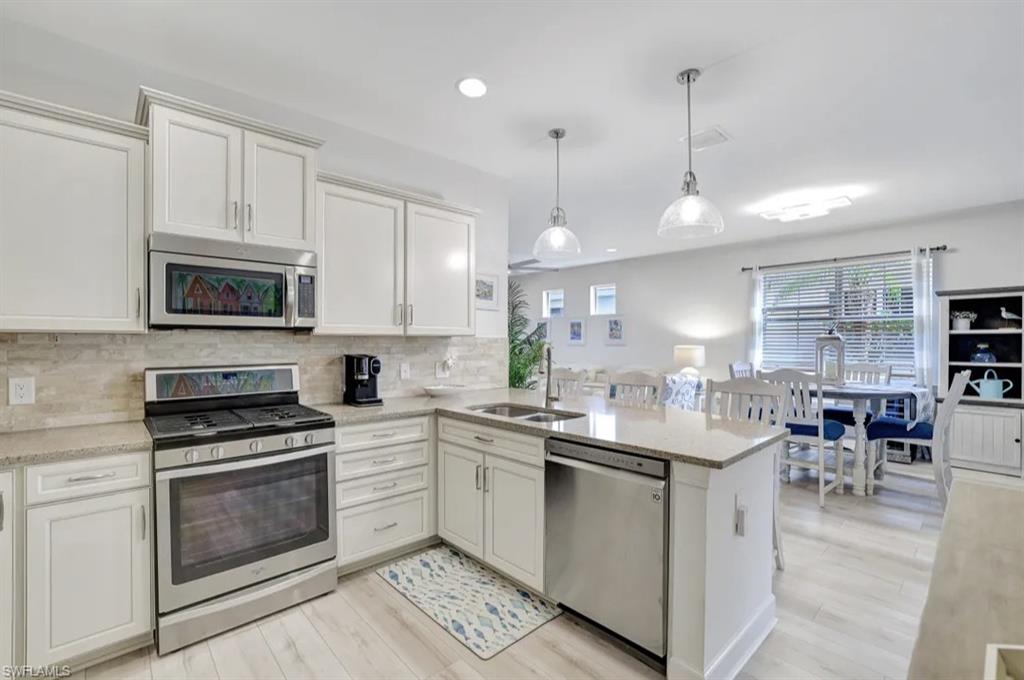 20183 Torch Key Way Estero, FL 33928 - Photo 4 of 30 Kitchen with stainless steel appliances, hanging light fixtures, light countertops, white cabinetry, and recessed lighting