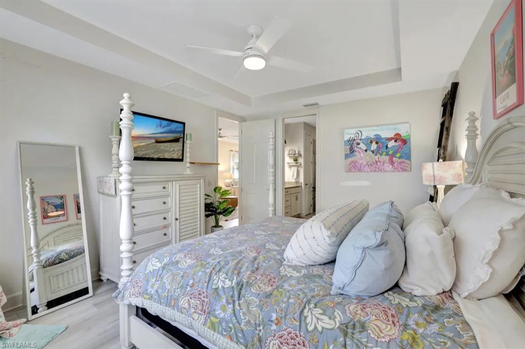 20183 Torch Key Way Estero, FL 33928 - Photo 9 of 30 Bedroom featuring light wood-style floors, ceiling fan, a raised ceiling, and ensuite bathroom