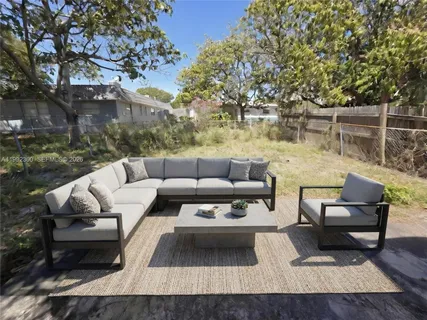 a view of a patio with couches and a table and chairs with wooden floor and fence