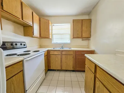 a kitchen with a sink a stove top oven and cabinets