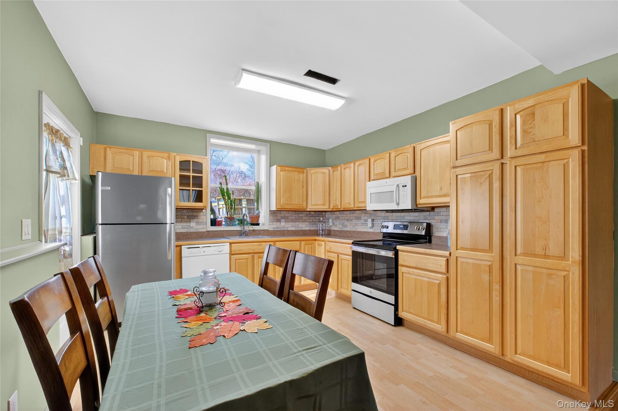 387 Cornwall Hill Road Patterson, NY 12563 - Photo 17 of 43 Apartment Kitchen featuring light brown cabinetry, tile counters, stainless steel appliances, backsplash, and glass insert cabinets