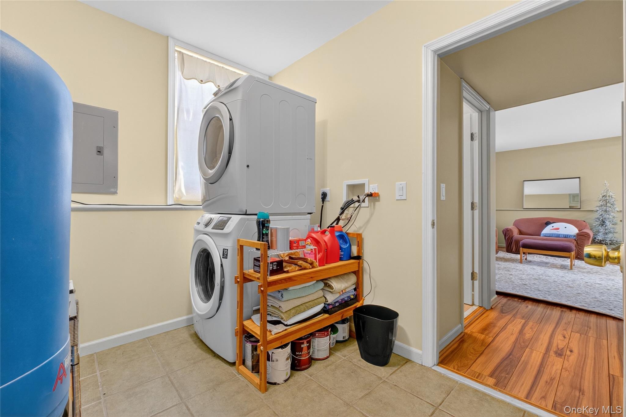 387 Cornwall Hill Road Patterson, NY 12563 - Photo 29 of 50 Laundry area separating apartment & bar area featuring stacked washing machine and dryer, electric panel, and light tile patterned floors