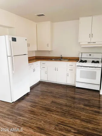 a kitchen with wooden floors and white appliances