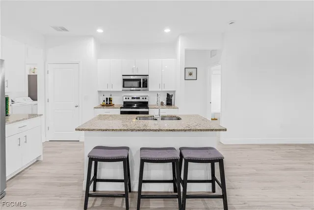 a kitchen with granite countertop a table chairs microwave and refrigerator