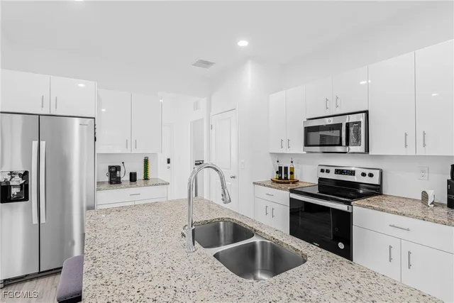 a kitchen with stainless steel appliances granite countertop a sink stove and refrigerator