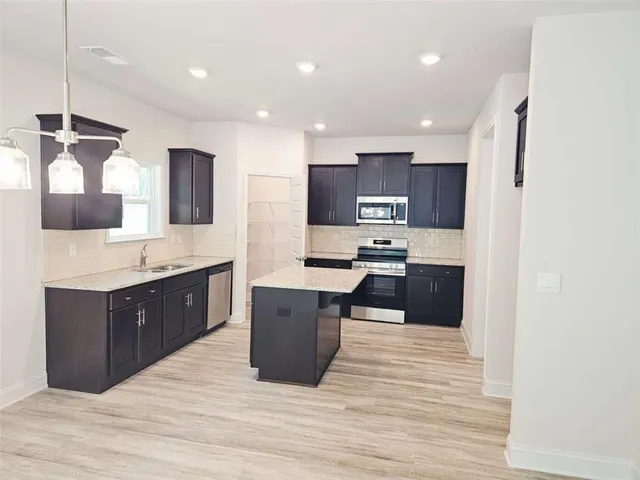 a large kitchen with stainless steel appliances kitchen island granite countertop a sink counter space and cabinets
