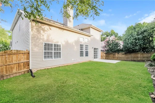 a backyard of a house with plants and large tree