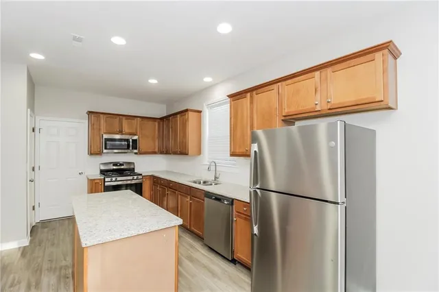 a kitchen with stainless steel appliances granite countertop a refrigerator a stove a sink dishwasher and a refrigerator with wooden floor