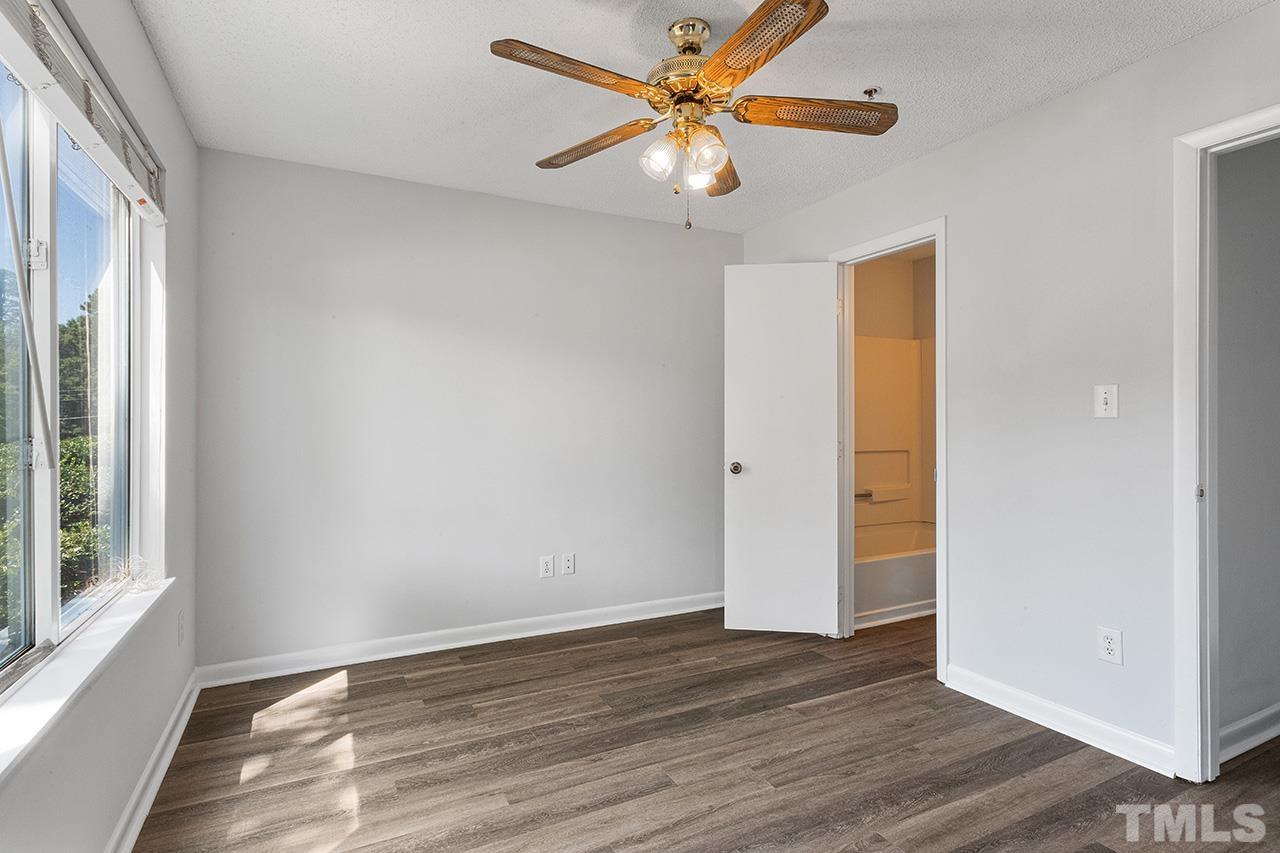 1241 University Court, Unit 2 Raleigh, NC 27606 - Photo 29 of 34 an empty room with wooden floor chandelier fan and windows