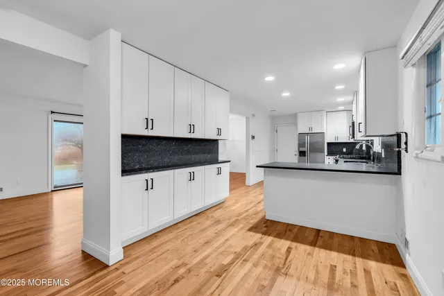 a large white kitchen with wooden floor