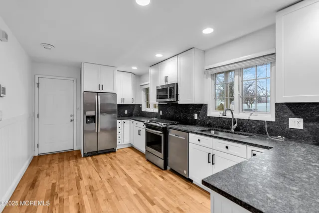 a kitchen with stainless steel appliances granite countertop a sink stove refrigerator and cabinets
