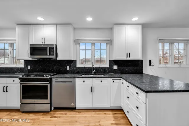 a kitchen with granite countertop a stove a sink and a microwave