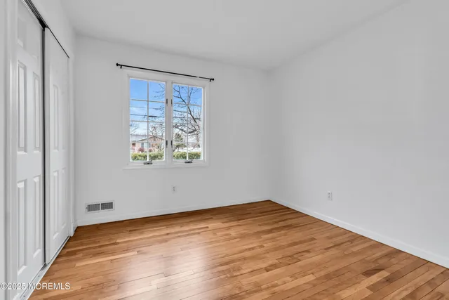 an empty room with wooden floor and window