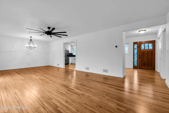 a view of empty room with wooden floor and ceiling fan