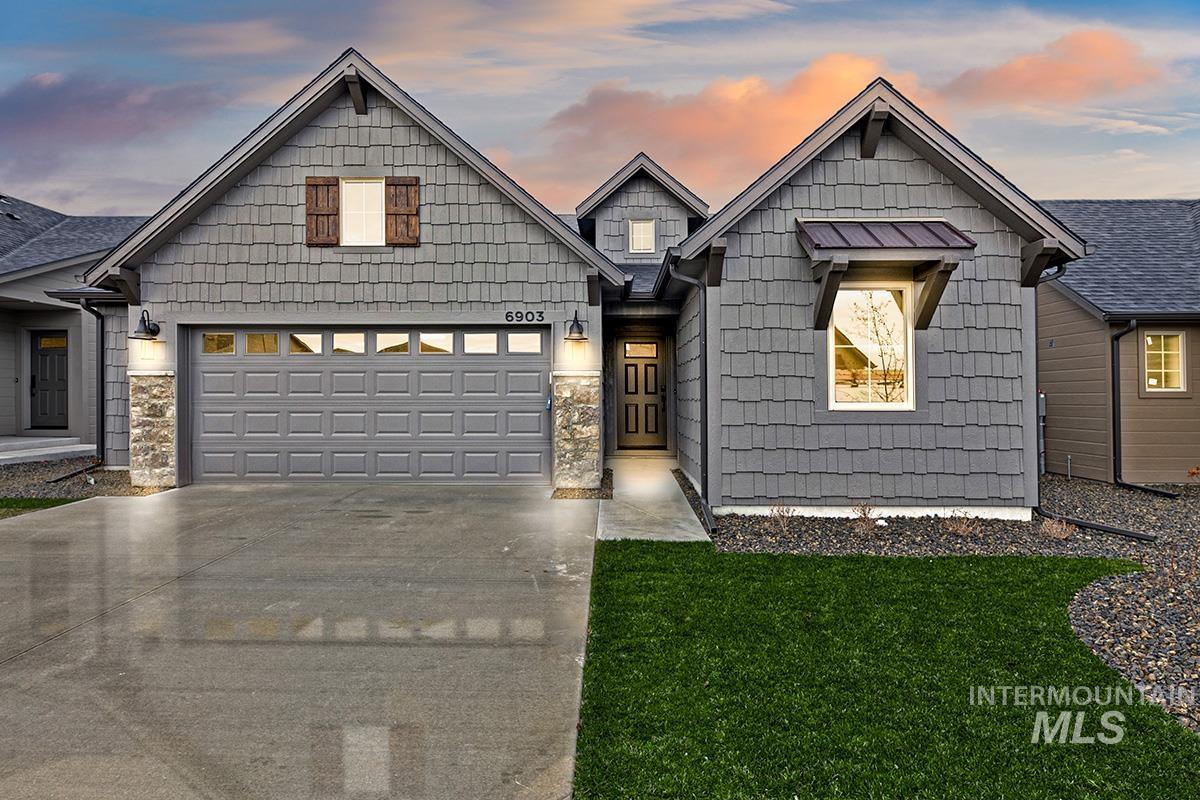 Craftsman-style house featuring concrete driveway, a front lawn, and stone siding