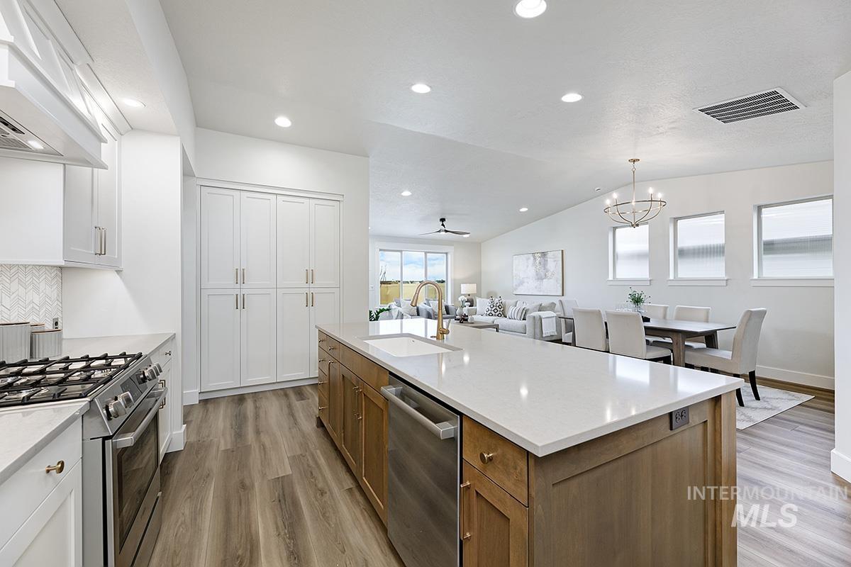 6975 South Skybreak Lane Meridian, ID 83642 - Photo 29 of 29 Two tone kitchen featuring dual tone cabinets, ceiling fan, stainless steel appliances, open floor plan, and light wood-style flooring