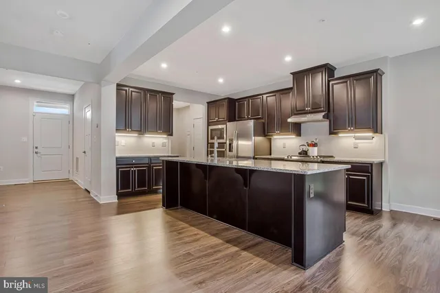 a kitchen with stainless steel appliances kitchen island granite countertop a refrigerator and a stove top oven