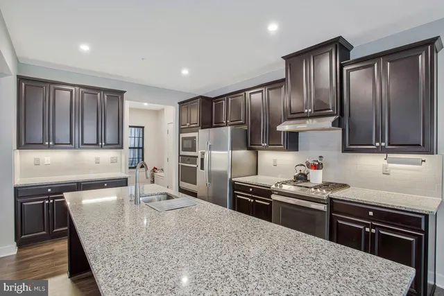 a kitchen with stainless steel appliances granite countertop a sink stove and refrigerator