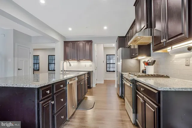 a kitchen with stainless steel appliances granite countertop a stove a sink and a refrigerator