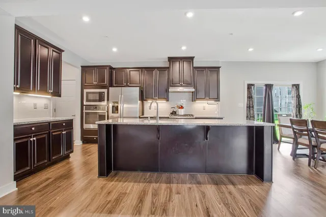 a kitchen with kitchen island granite countertop wooden floors and stainless steel appliances