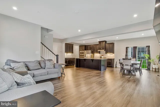 a living room with furniture and kitchen view with wooden floor