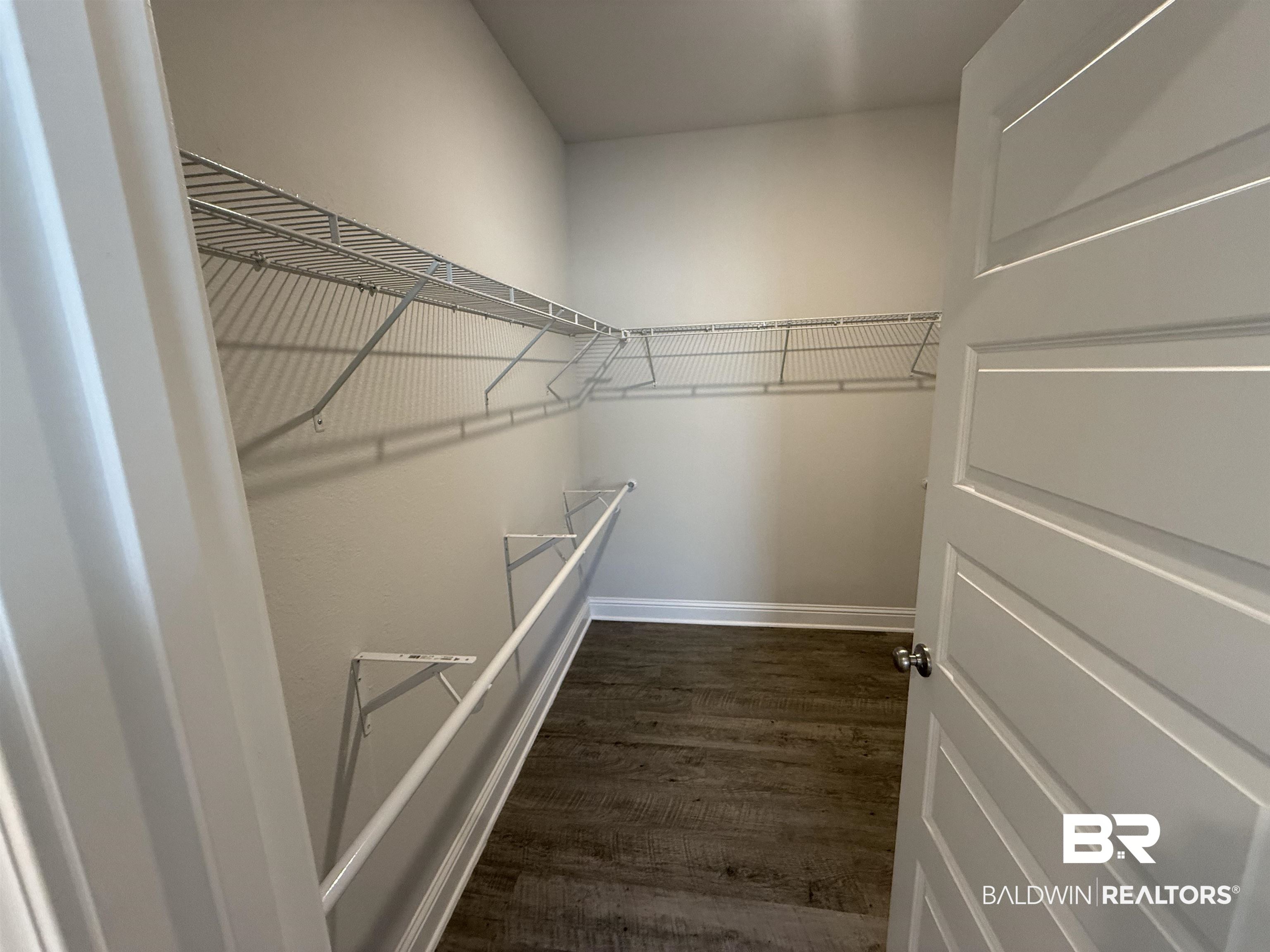 23247 Lieutenant Avenue Foley, AL 36535 - Photo 34 of 47 Spacious walk-in closet featuring wire shelving, wire hanging rods, gray wall paint, white baseboards, and wood-finish flooring