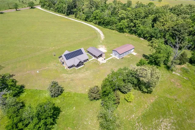 an aerial view of residential houses with outdoor space and trees all around