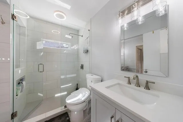 a bathroom with a sink toilet a mirror and shower