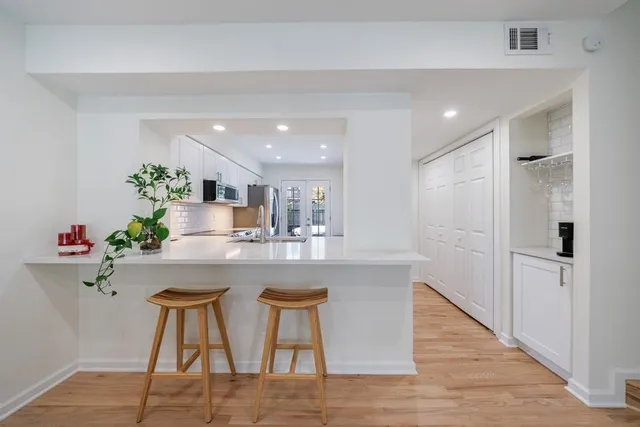 a kitchen with white cabinets and wooden floor