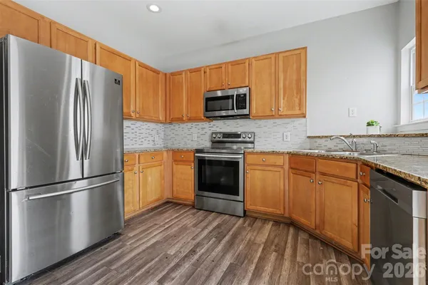 a kitchen with granite countertop stainless steel appliances a sink and refrigerator