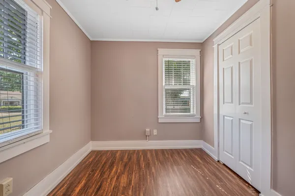 a view of an empty room with wooden floor and a window