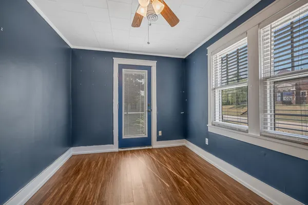 a view of an empty room with wooden floor and a window