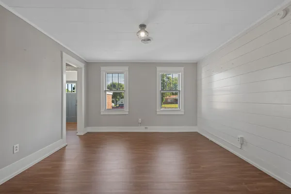 an empty room with wooden floor and windows