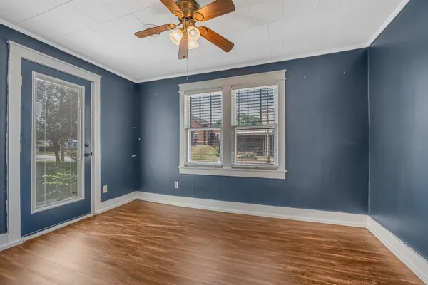 a view of an empty room with wooden floor and a window
