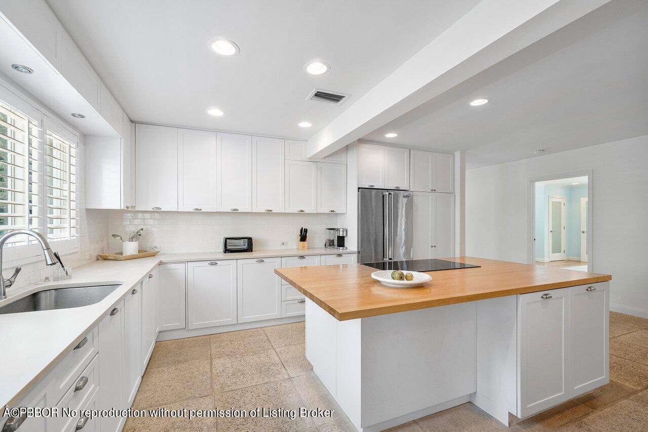 256 Mockingbird Trail Palm Beach, FL 33480 - Photo 6 of 31 a kitchen with stainless steel appliances granite countertop a sink dishwasher and a refrigerator with wooden cabinets