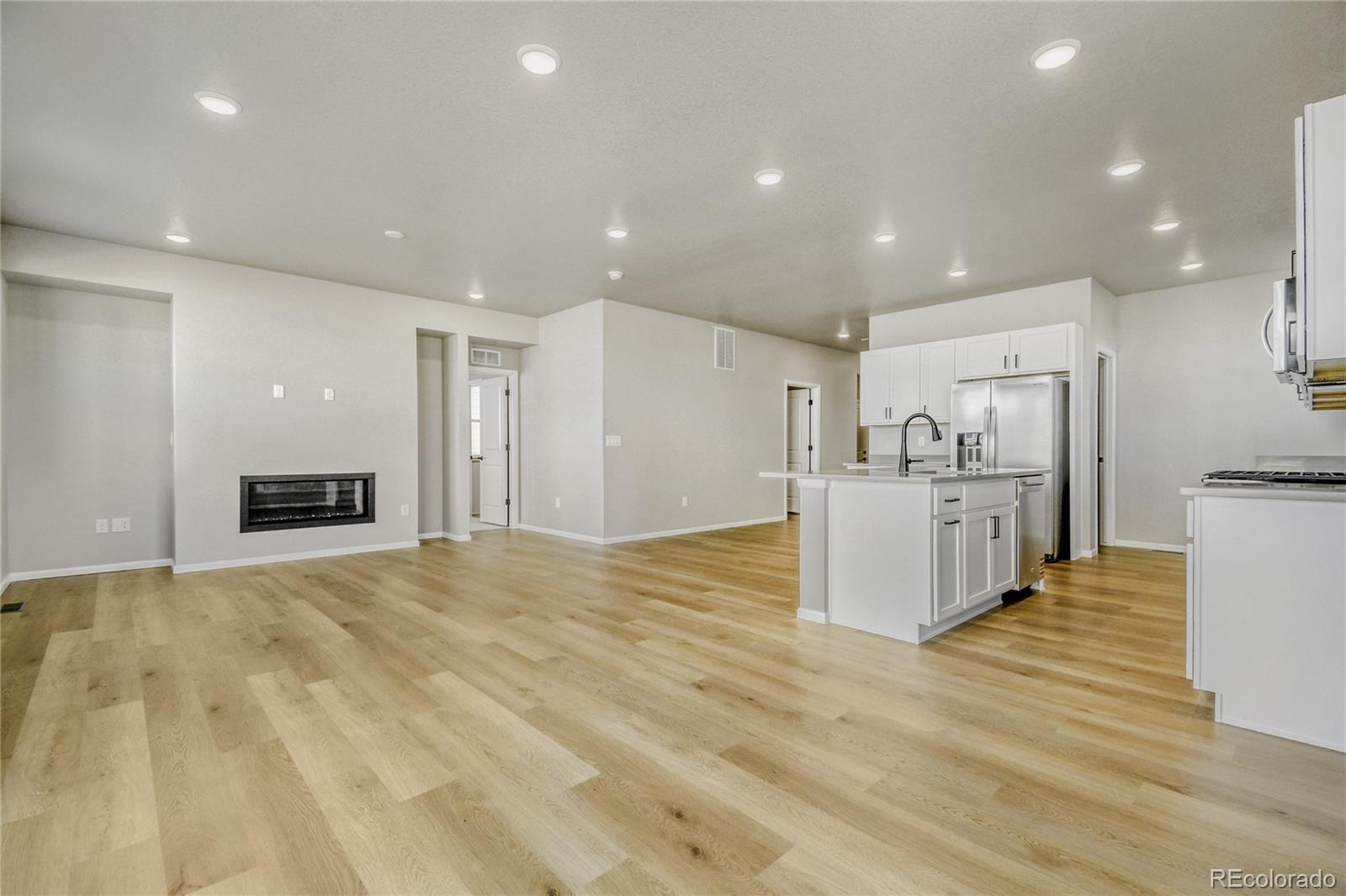 4135 Runyon Street Brighton, CO 80601 - Photo 13 of 27 a view of kitchen and empty room with wooden floor