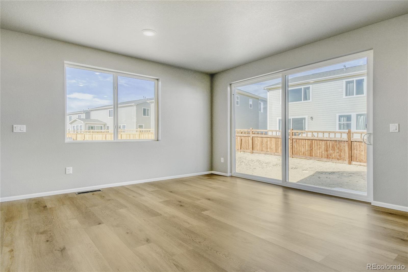 4135 Runyon Street Brighton, CO 80601 - Photo 9 of 27 an empty room with wooden floor and windows