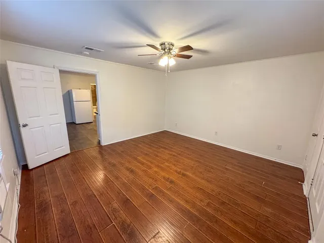an empty room with wooden floor and a ceiling fan