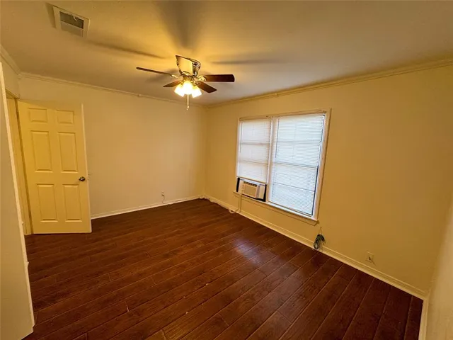 a view of empty room with wooden floor and fan