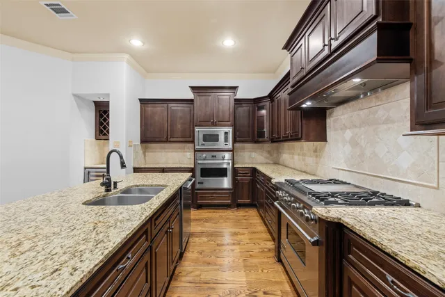 a kitchen with kitchen island granite countertop a sink stainless steel appliances and cabinets