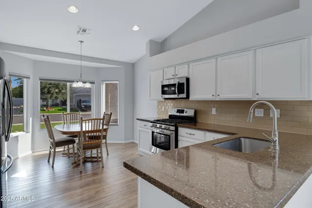 a kitchen with kitchen island a dining table chairs stainless steel appliances and cabinets
